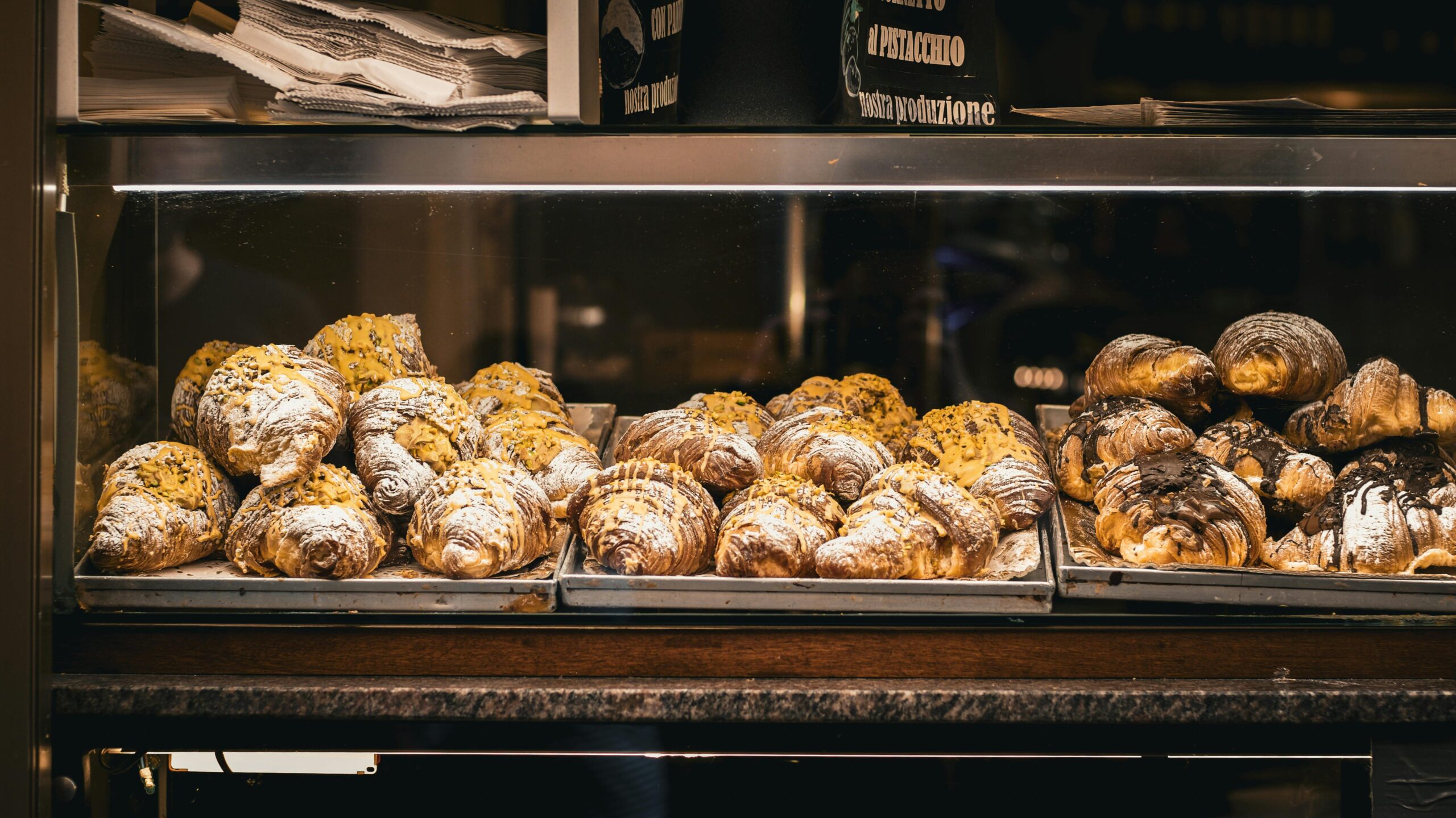A tempting selection of fresh croissants displayed in a bakery window in Rome, Italy.